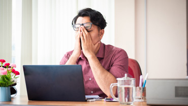 Väsynyt henkilö tietokoneen ääressä