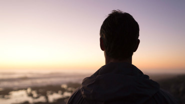 Mies katsoo auringonlaskua